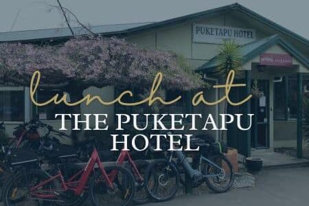 Things to Do in Hawke's Bay | Eat Lunch at the Puketapu Hotel | Porters Boutique Hotel - Text over green weatherboard building with cherry blossom tree.